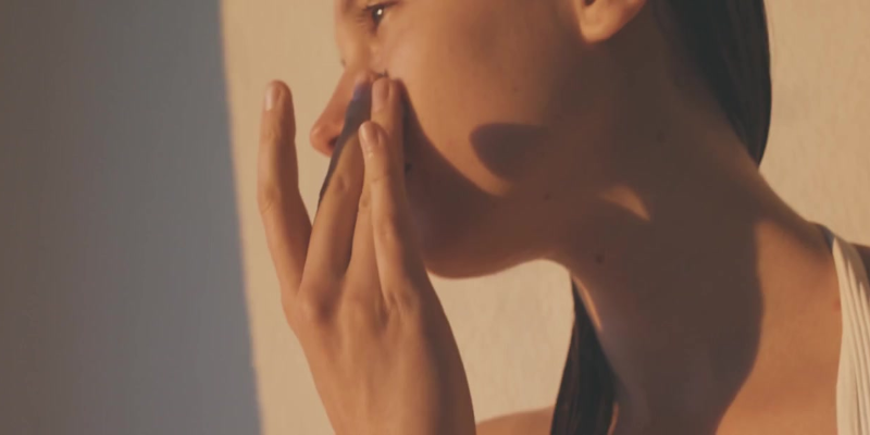 Lady applying sunscreen on face with sunshining
